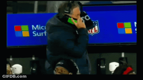 A Football Player Talking On A Cell Phone With A Microsoft Surface Advertisement Behind Him GIF