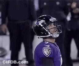 A Football Player Wearing A Black Helmet And A Purple Jersey Is Standing On The Field . GIF