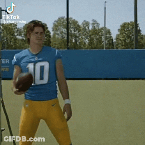 A Football Player Wearing A Blue And Yellow Uniform Is Holding A Football . GIF