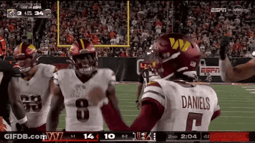 A Football Player Wearing A Daniels Jersey Is Standing On The Field With His Teammates GIF