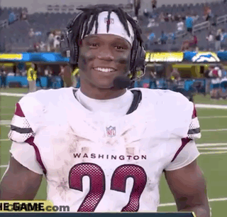 A Football Player Wearing A Headband And Headphones Is Standing On A Field . GIF
