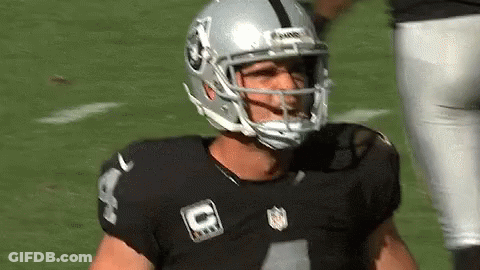 A Football Player Wearing A Helmet And A Black Jersey Is Standing On The Field . GIF