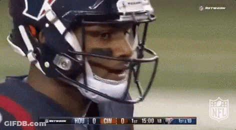 A Football Player Wearing A Helmet And A Mask Is Standing On A Field . GIF