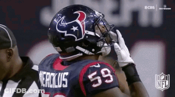 A Football Player Wearing A Helmet And Gloves Is Talking On A Cell Phone . GIF