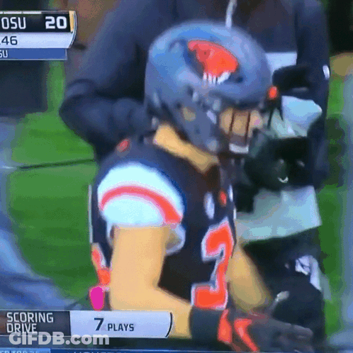 A Football Player Wearing A Helmet Is Sitting On A Field With A Scoreboard That Says Scoring Drive GIF