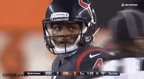 A Football Player Wearing A Helmet Is Standing On A Field . GIF