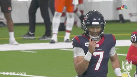 A Football Player Wearing A Helmet Is Standing On A Field With His Finger On His Mouth . GIF