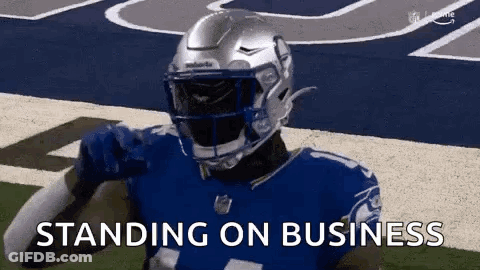 A Football Player Wearing A Helmet Is Standing On A Field With The Words `` Standing On Business '' . GIF