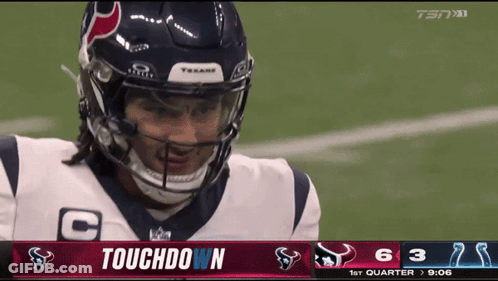 A Football Player Wearing A Helmet Stands In Front Of A Touchdown Screen GIF