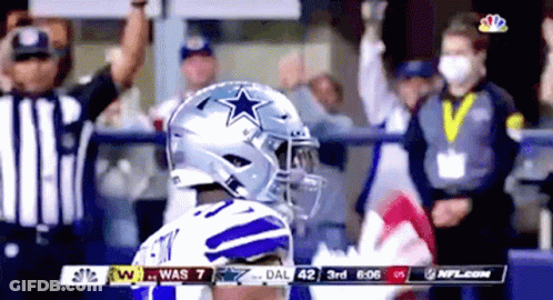 A Football Player Wearing A Helmet With A Star On It Stands In Front Of A Crowd During A Game . GIF