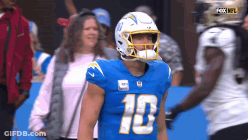 A Football Player Wearing A Helmet With The Number 10 On It Stands On The Field . GIF