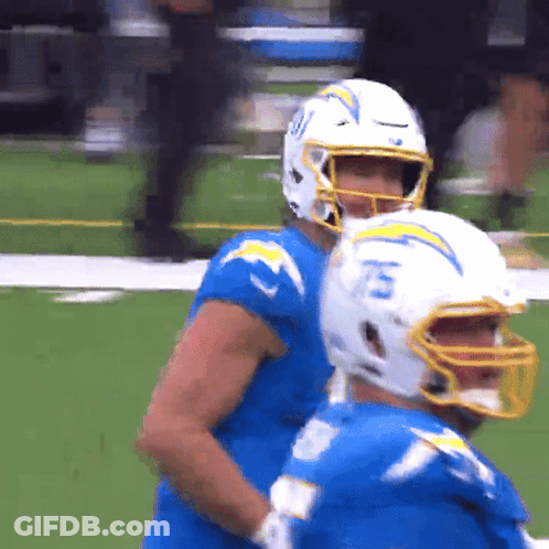 A Football Player Wearing A Helmet With The Number 15 On It Stands Next To Another Player GIF