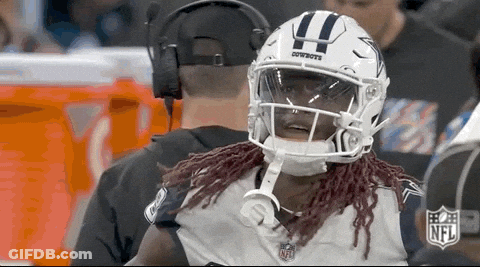 A Football Player Wearing A Helmet With The Word Cowboys On It Is Talking To A Referee . GIF