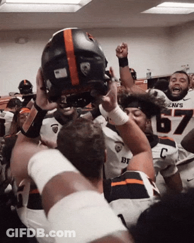 A Football Player Wearing A Jersey That Says Beavs Is Holding Up His Helmet GIF