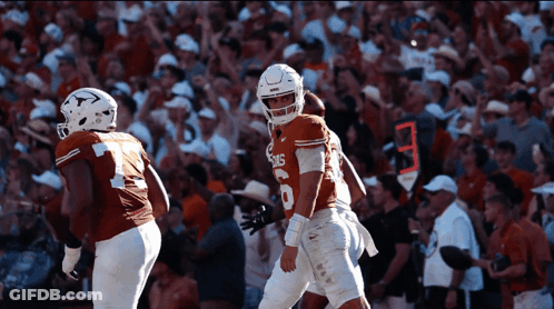 A Football Player Wearing A Jersey That Says Texas Stands In Front Of A Crowd GIF