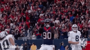 A Football Player Wearing A Jersey With The Number 90 On It Is Running In Front Of A Crowd During A Game . GIF