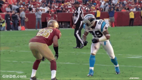 A Football Player Wearing A Number 19 Jersey Stands In Front Of Another Player Wearing A Number 26 Jersey GIF