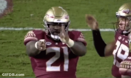 A Football Player Wearing A Number 21 Jersey Is Pointing At The Camera . GIF