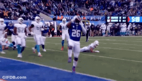 A Football Player Wearing A Number 26 Jersey Is Running On The Field . GIF