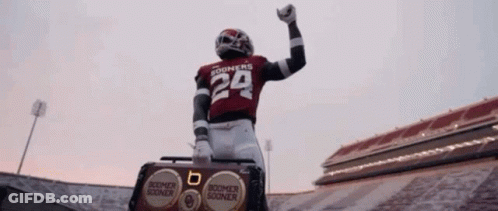 A Football Player Wearing A Number 29 Jersey Is Standing On Top Of A Boombox In A Stadium . GIF
