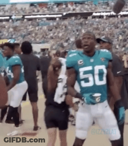 A Football Player Wearing A Number 50 Jersey Is Standing In Front Of A Crowd Of People . GIF