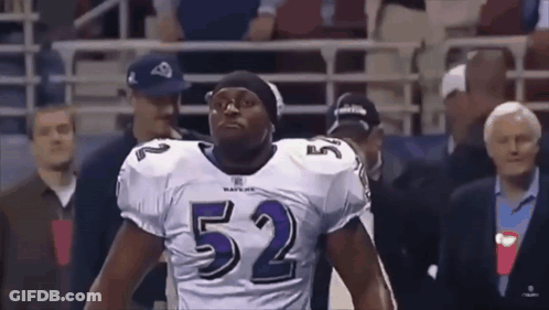 A Football Player Wearing A Number 52 Jersey Stands In Front Of A Crowd . GIF