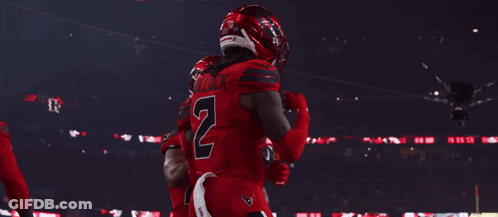 A Football Player Wearing A Number 7 Jersey Stands In A Huddle With His Teammates GIF