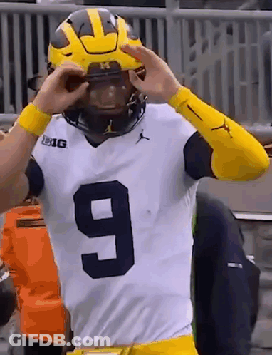 A Football Player Wearing A Number 9 Jersey Is Putting On His Helmet . GIF
