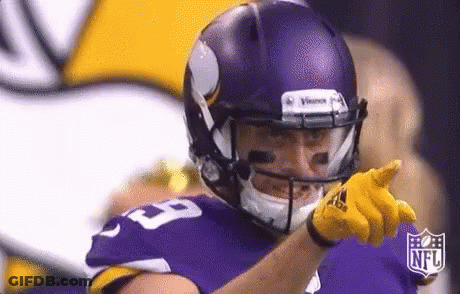 A Football Player Wearing A Purple Helmet And Yellow Gloves Is Pointing . GIF