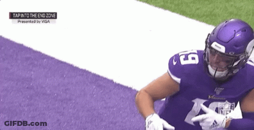 A Football Player Wearing A Purple Jersey And A Purple Helmet Is Sitting On The Field . GIF