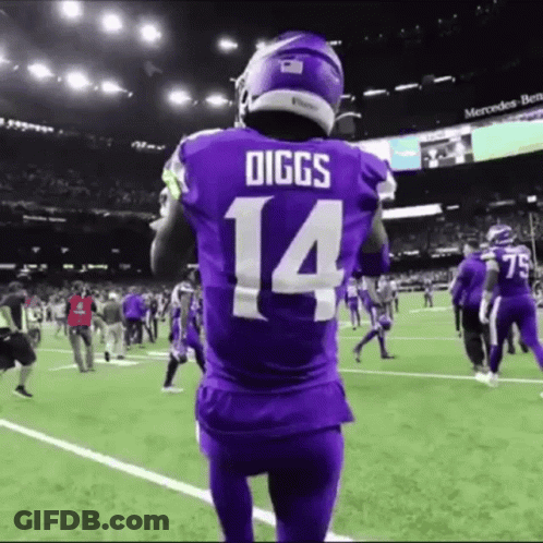 A Football Player Wearing A Purple Jersey With The Number 14 On It Stands On A Field . GIF