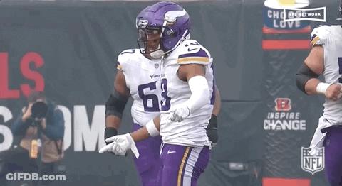 A Football Player Wearing A Purple Uniform With The Number 68 On It GIF