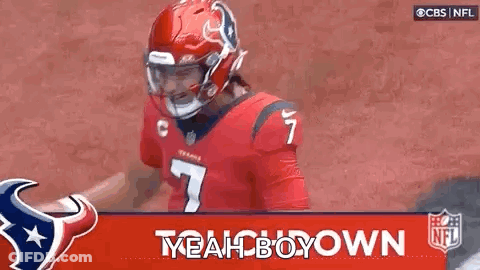 A Football Player Wearing A Red Helmet And A Red Jersey Is Standing In Front Of A Banner That Says Yeah Boy Down . GIF