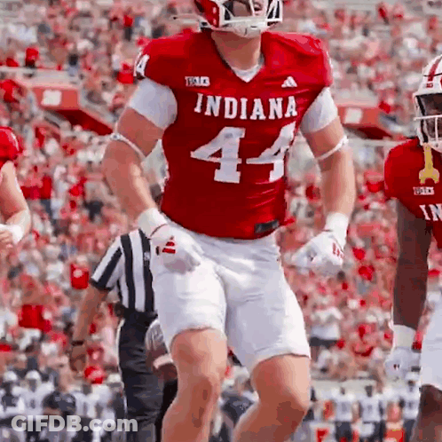 A Football Player Wearing A Red Indiana Jersey And White Shorts Is Running On The Field . GIF