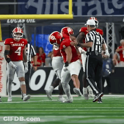 A Football Player Wearing A Red Indiana Jersey Is Being Tackled By Another Player GIF