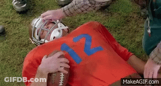A Football Player Wearing A Red Jersey With The Number 12 On It Is Laying On The Ground . GIF