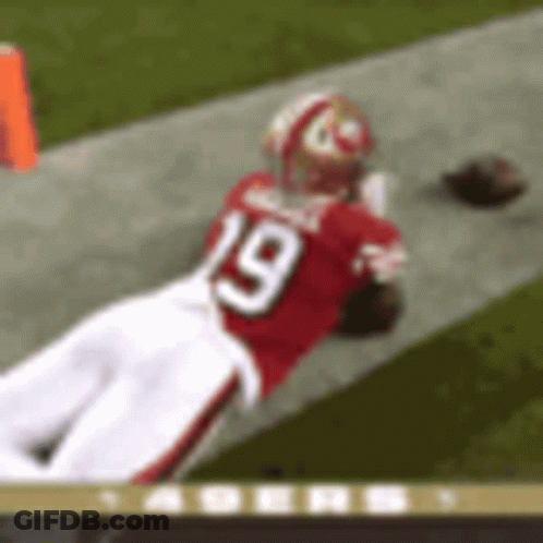 A Football Player Wearing A Red Jersey With The Number 19 On It Is Laying On The Field . GIF