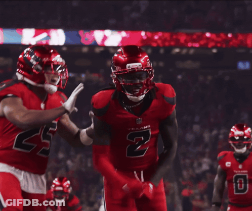 A Football Player Wearing A Red Jersey With The Number 2 On It Is Being Hugged By Another Player GIF