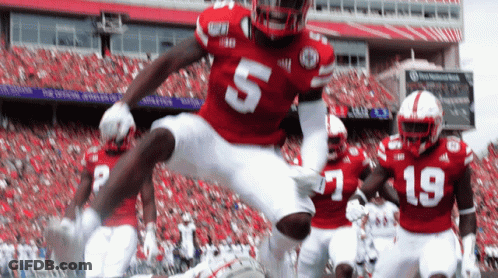 A Football Player Wearing A Red Jersey With The Number 5 Jumps In The Air GIF
