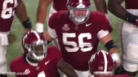 A Football Player Wearing A Red Jersey With The Number 55 On It Is Running On The Field . GIF