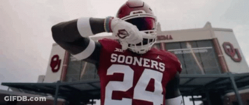 A Football Player Wearing A Sooners Jersey Is Standing In Front Of A Stadium . GIF