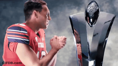 A Football Player Wearing A Utah Jersey Stands Next To A Trophy GIF