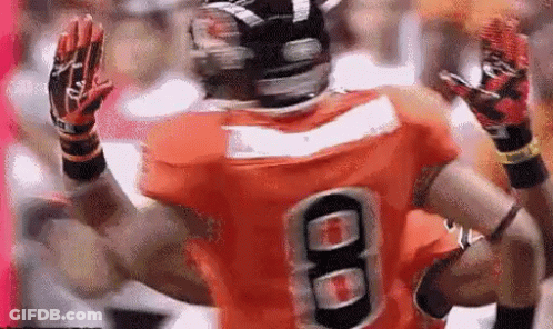 A Football Player Wearing An Orange Jersey With The Number 8 GIF