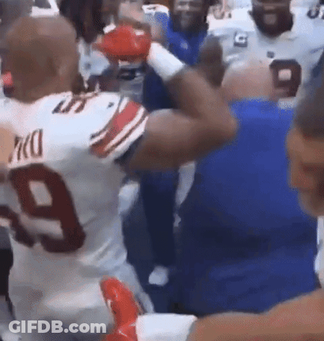 A Football Player Wearing Boxing Gloves Is Standing In A Crowd Of People . GIF