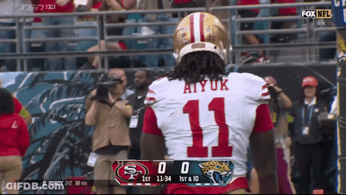 A Football Player Wearing Number 11 Stands In Front Of A Scoreboard GIF