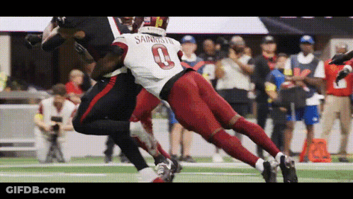 A Football Player Wearing The Number 0 Jersey Is Being Tackled By Another Player GIF