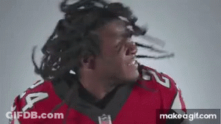 A Football Player With Dreadlocks Is Making A Funny Face While Wearing A Red Jersey . GIF