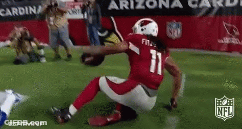 A Football Player With The Number 11 On His Jersey Is Kneeling On The Field While Holding A Football . GIF