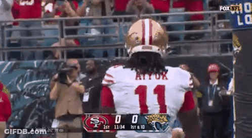 A Football Player With The Number 11 On His Jersey Stands In Front Of A Scoreboard . GIF