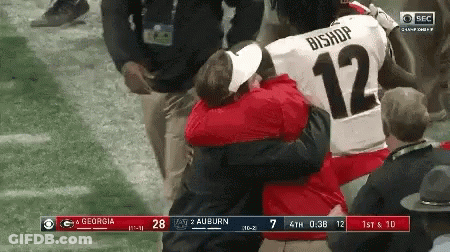A Football Player With The Number 12 On His Jersey Is Hugging Another Player GIF